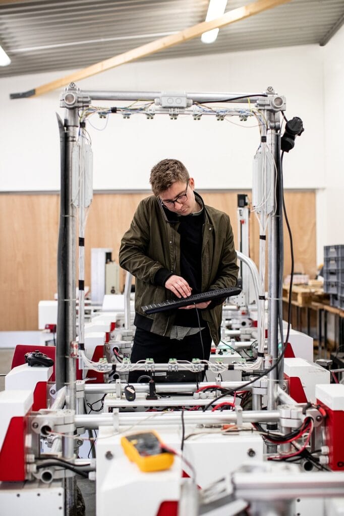 Man using a keyboard to control a manufacturing robot. A multi-meter is in the foreground.