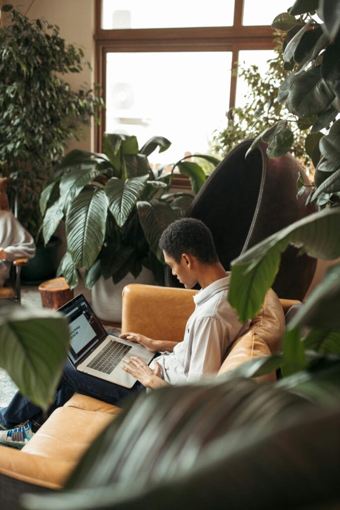 Diligent young accountant working in a plant-filled modern office lounge.