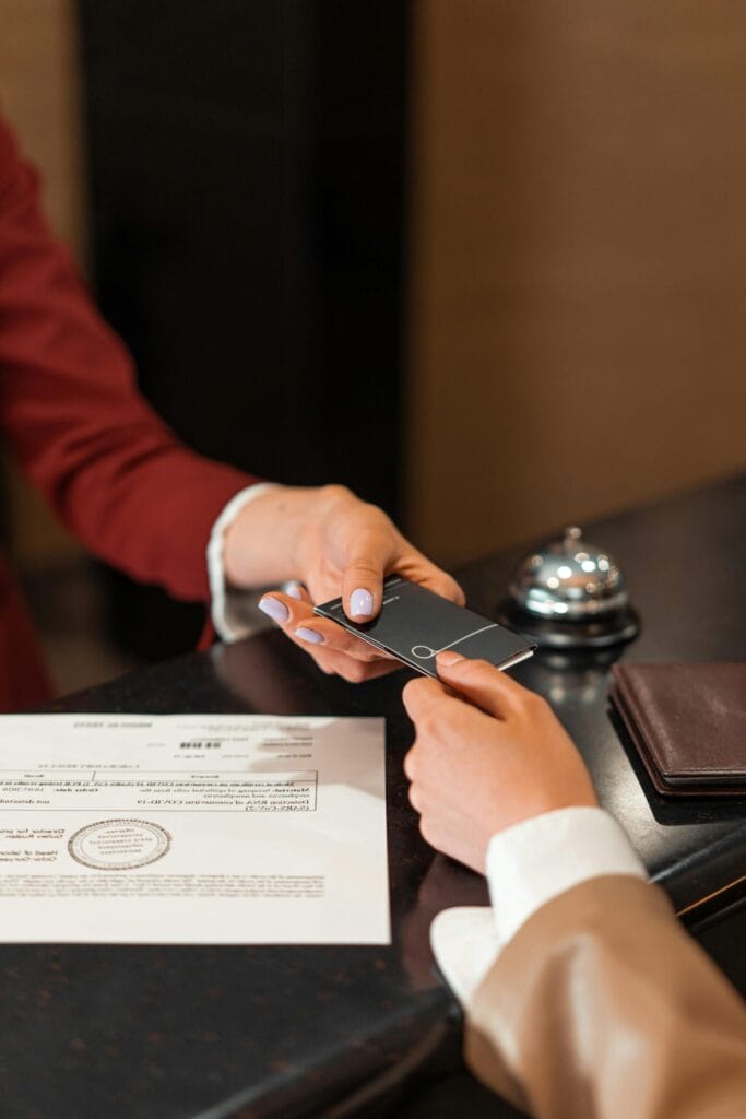 A hotel receptionist hands an electronic key card to a guest over the counter